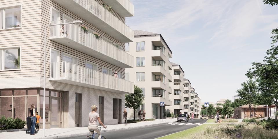 Bostadshus med balkonger placerade längs gata med cyklist. 