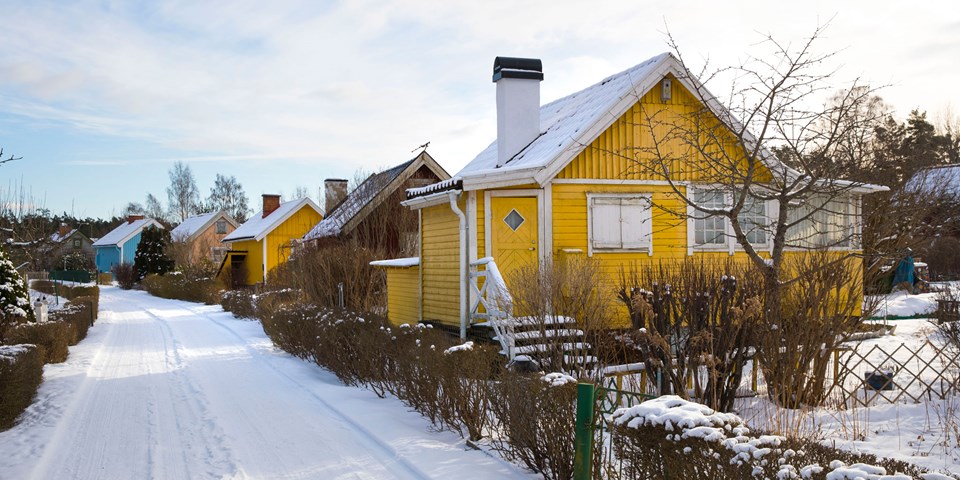 Färgglada småhus längs väg i vinterlandskap, foto.