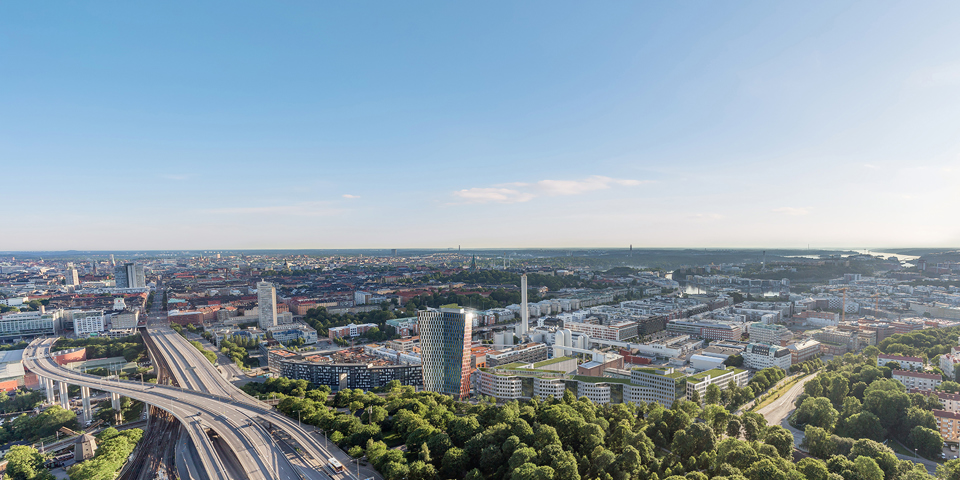Flygvy över byggnader, grönområden, vägar och kollektivtrafikspår, fotografi.