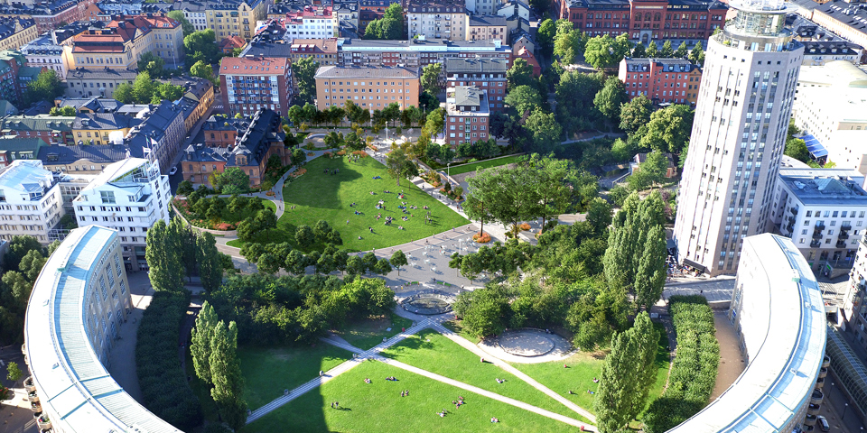 Flygvy över grönområde med flerbostadshus i halvcirkel och andra flerbostadshus runt om, fotomontage.