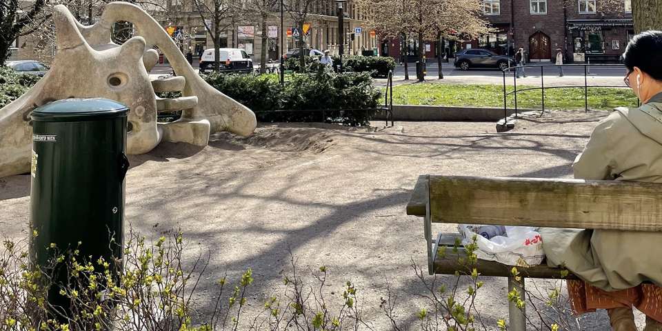 Vy bakifrån på en kvinnan som sitter på en bänk i parken.