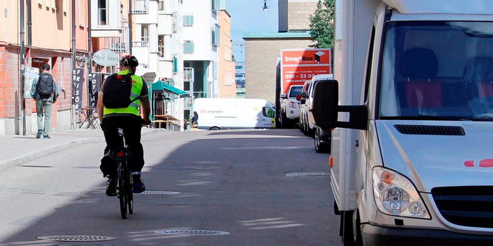 Cyklist cyklar förbi en vit skåpbil på Repslagargatan.