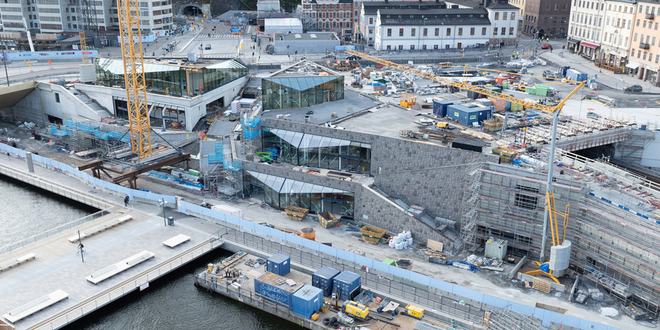 Byggarbetsplatsen vid Slussen. Vy ovanifrån över byggnation av Mälarterrassen med glaspaviljonger och fasader av granit. I bakgrunden ligger Ryssgården och Katarinahuset.