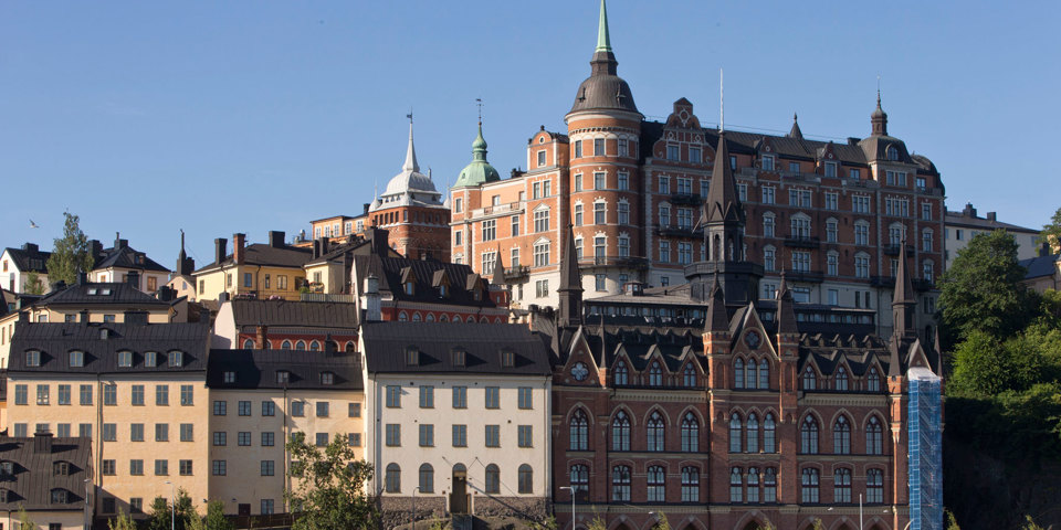 Flervåningshus i äldre stil och olika färger längs Söder Mälarstranden. Solig dag.