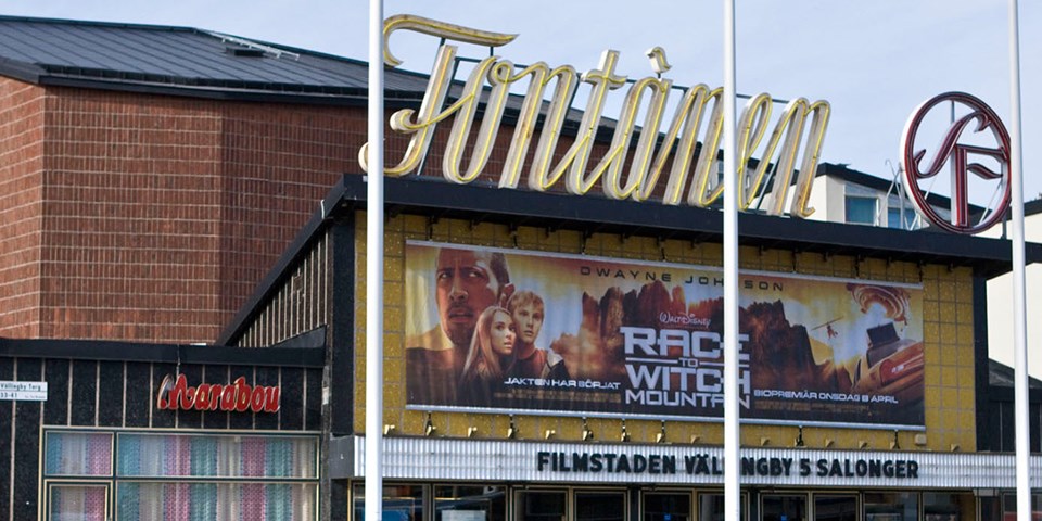 Biografen Fontänen sett från torget. På taket finns ljusskyltar och över ingången hänger reklam för en film som visas.