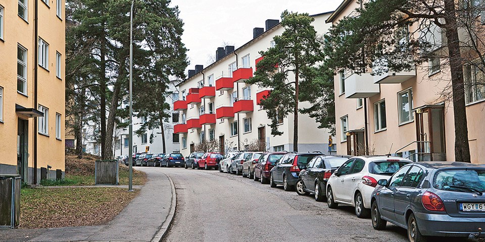 Bild på tre smalhus och en gata med grönska mellan.