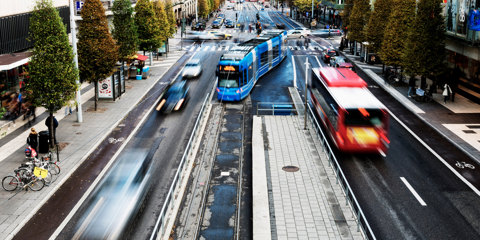 En spårvagn anländer till en hållplats samtidigt som en buss åker i motsatt riktning.