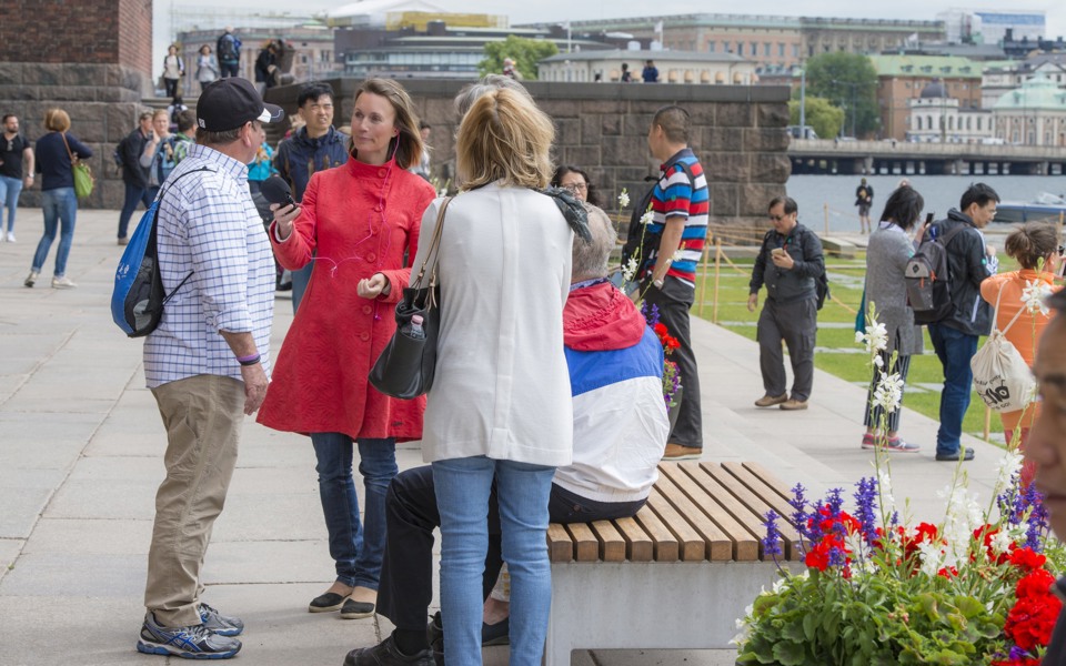 Kvinna i rött intervjuar man i keps utanför stadshuset.  Människor i bakgrunden.