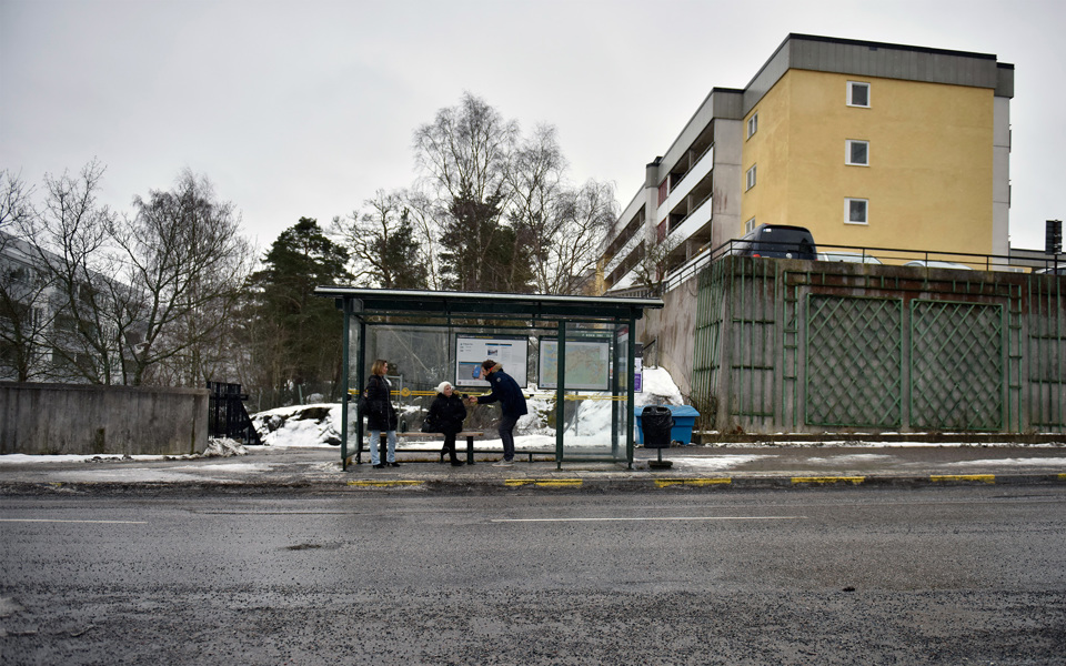 Kvinna intervjuas vid busshållsplats vid väg. Betong och snöslask i bakgrunden. 