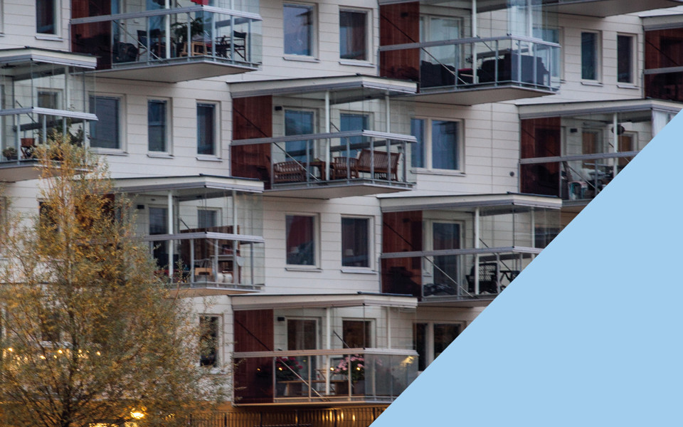 Närbild på ett vitt nyare bostadshus med större balkonger