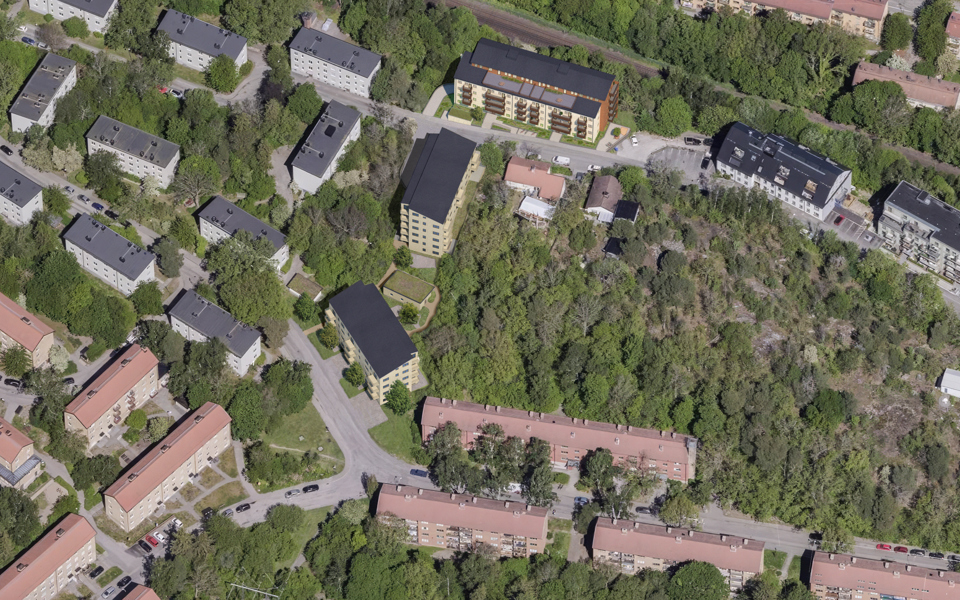 Flygfoto över hela förslaget. De tre nya huskropparna syns ovanifrån i mitten av bilden. Omkring visas befintlig bebyggelse