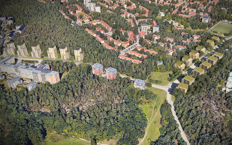Flygbild över skog och bostadsbebyggelse med både lägre och högre flervåningshus..