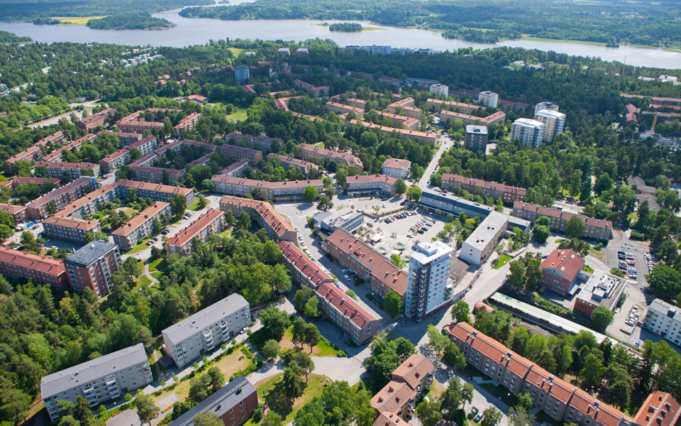 Flygvy över bostadshus och grönområden och vatten, foto.