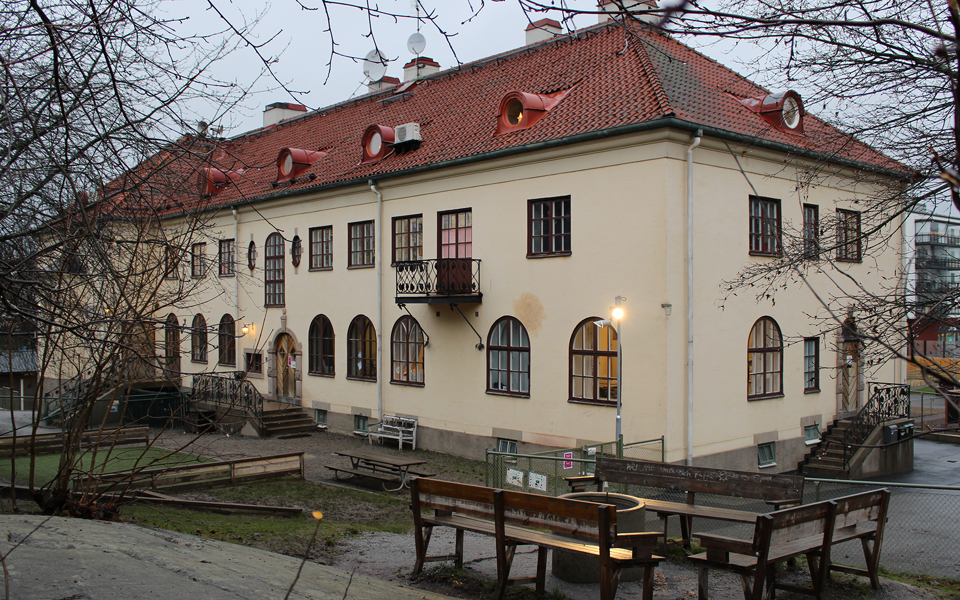 Gul byggnad i två våningar med välvda fönster på första våningen..