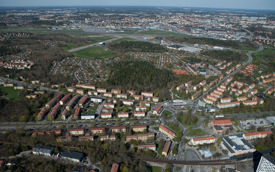 Vy över område med grönområden, vägar och hus. I mitten syns en rondell. 