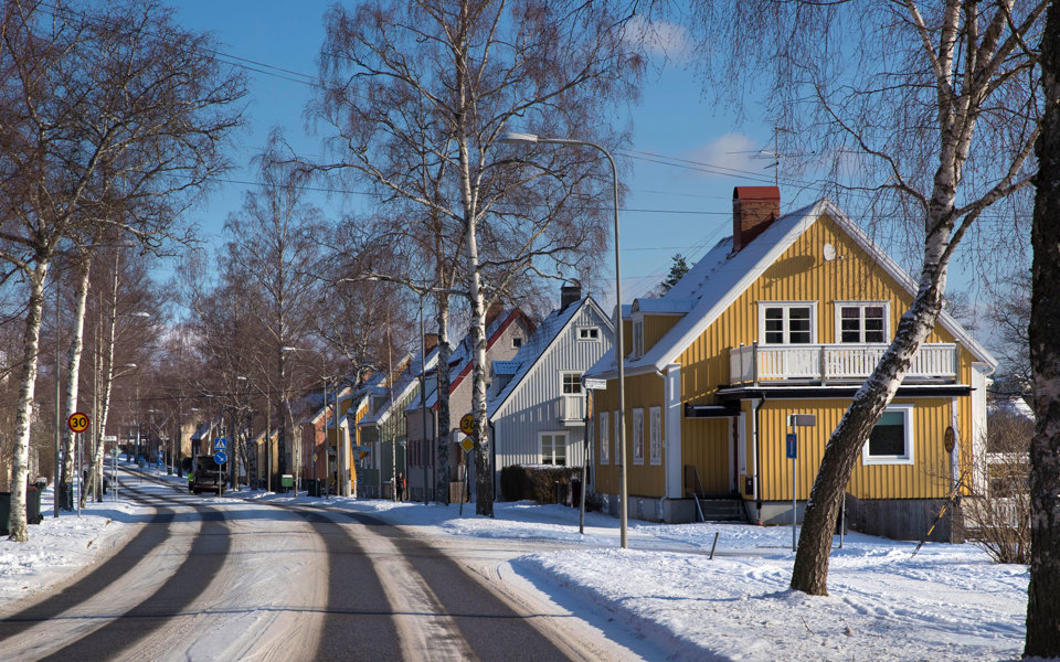 Färgglada trähus längs väg. Soligt vinterlandskap.