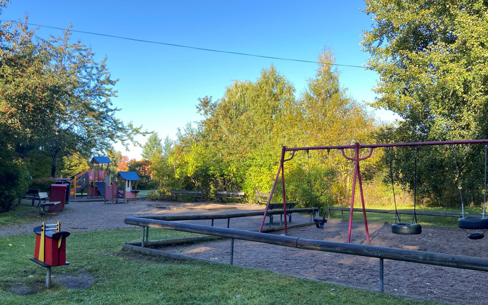 Lekplats med gungor, klätterställning och bänkar.