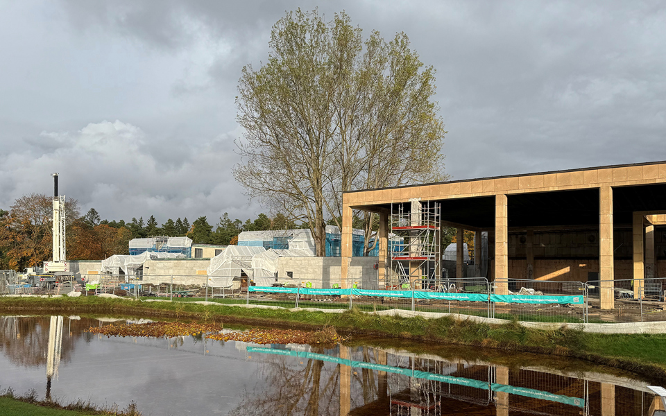 En byggnad i sten renoveras omgärdad av byggnadsställningar och presenningar. 
