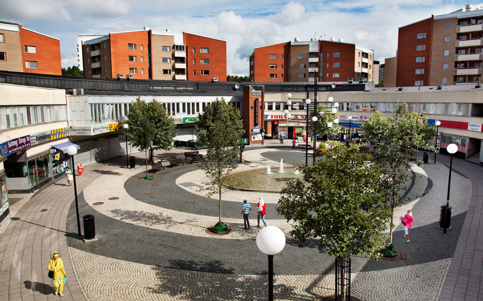 Runt torg med fontän i mitten fotat ovanifrån. Flervåningshus i bakgrunden., foto.