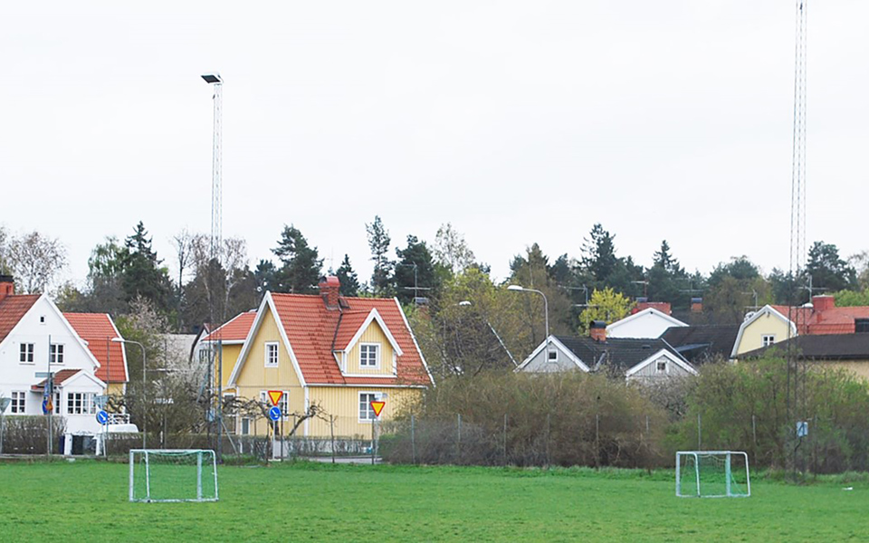 Villor som ligger vid en fotbollsplan och som är omgivna av träd. Foto.