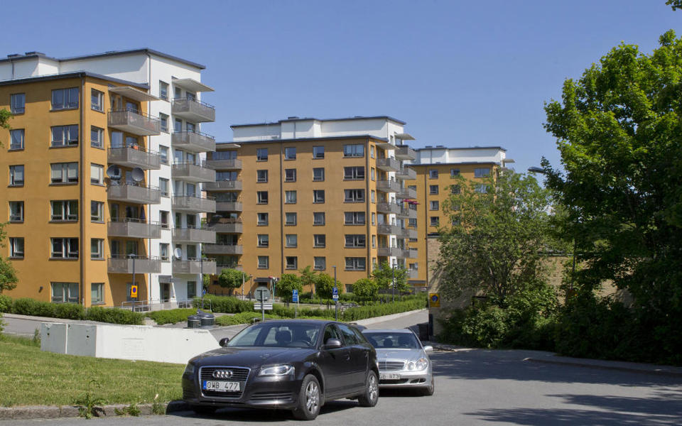 Flerbostadshus i orange, parkerade bilar, fotografi.