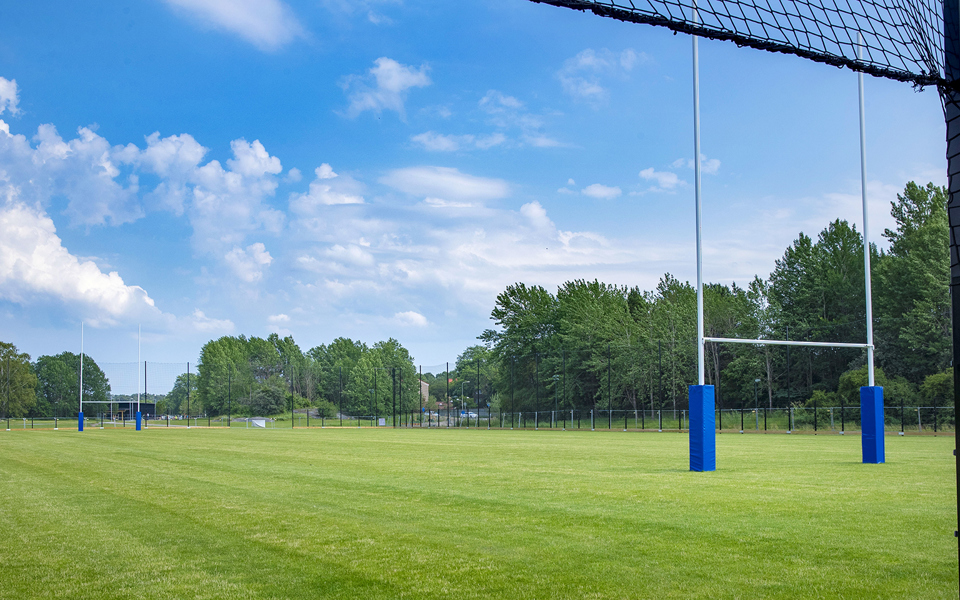 Rugbyplan med naturgräs och rugbymål, foto.