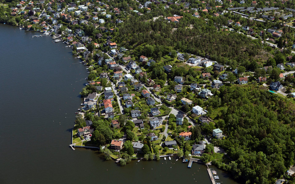 Flygvy över bostadshus, grönområden och vatten, foto.