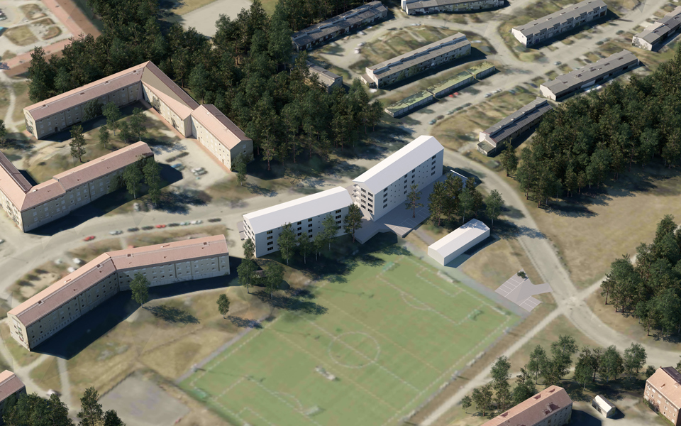 Flygfoto taget snett uppifrån där de nya flerbostadshusen och en stor bollplan visas.
