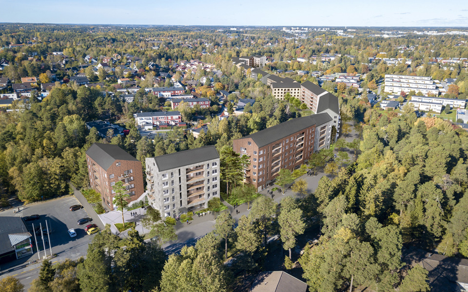 Ett flygfoto där man ser höga hus och radhus, vägar och trädkronor.