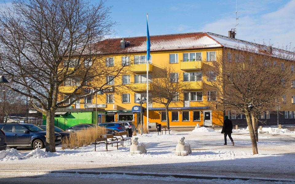 Litet torg, parkering, kiosk och gult flerbostadshus, fotografi.