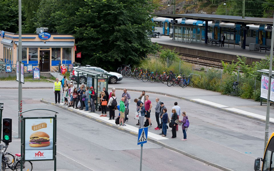 Människor i kö vid busshållplats i Spånga centrum, foto.