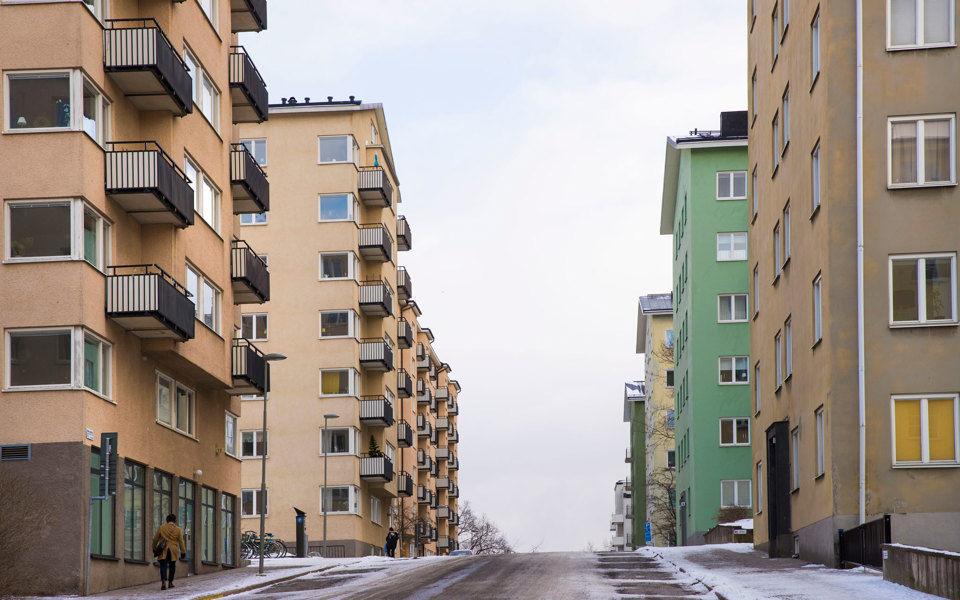 En gata med flerbostadshus på båda sidor. En människa i rörelse.