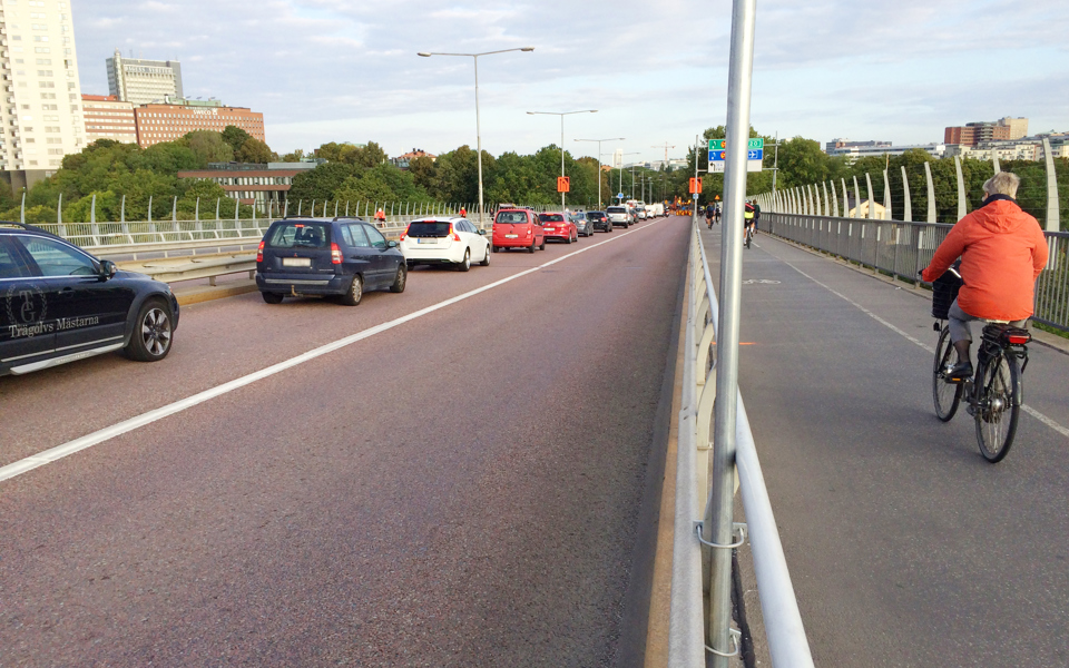Bro med bilväg och cykelbana. Cyklister som cyklar och bilar som kör, foto.