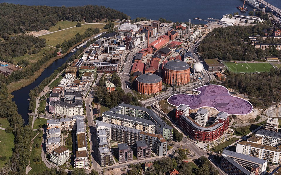Natur- och grönområden, vatten, bostadshus, gasklockor och fotbollsplan. Flygfoto.