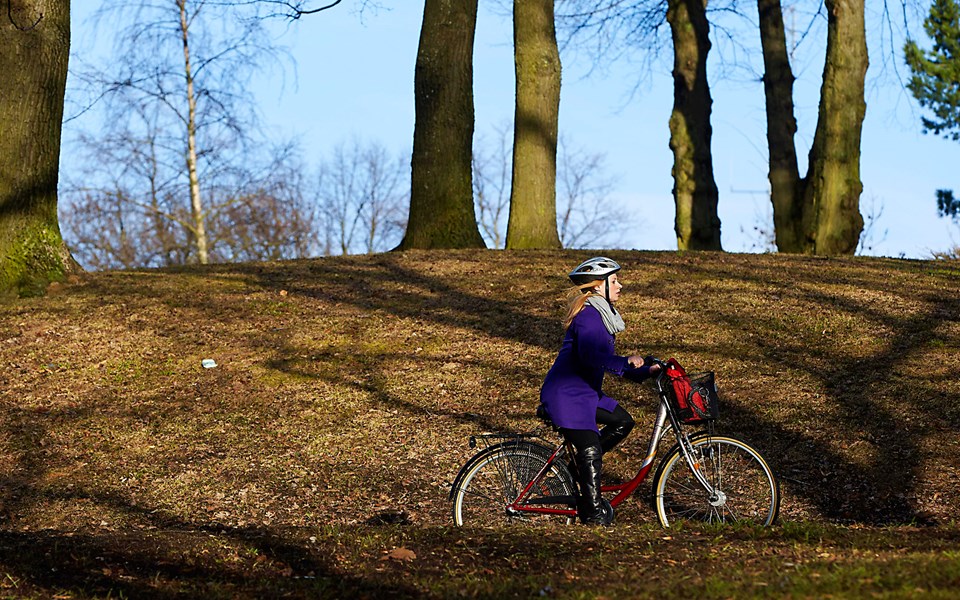 Kvinna på cykel i naturen. Foto.