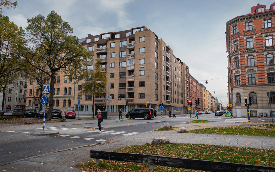 Bostadshus i tegel, träd och människor i rörelse som går mellan alléerna. Visualisering.