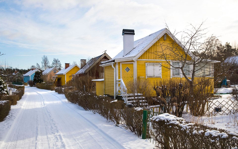Färgglada småhus längs väg i vinterlandskap, foto.