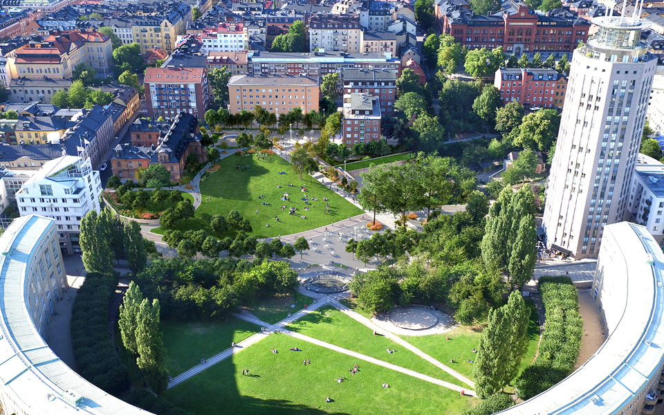 Flygvy över grönområde med flerbostadshus i halvcirkel och andra flerbostadshus runt om, fotomontage.