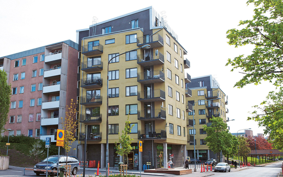 Två typiska lamellhus i sju våningar och separerad bil- och gångtrafik med gångbro över vägen i Spånga-Tensta.