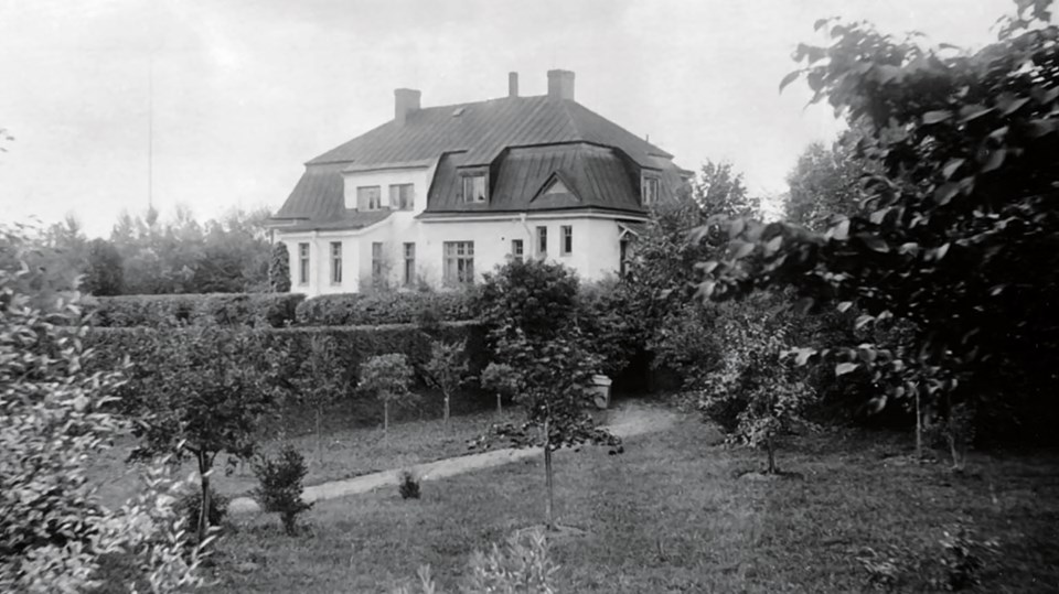 Gammalt svartvitt fotografi av en villa i en stor trädgård.
