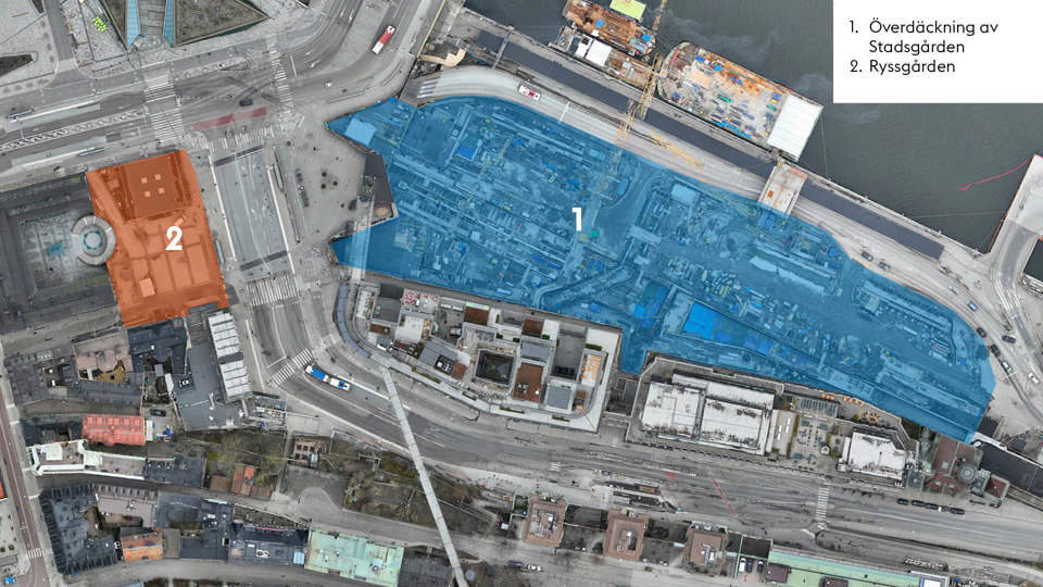 Flygfoto över Stadsgårdsområdet i Stockholm med två markerade arbetsområden. Ett stort blått område (markerat med siffran 1) täcker byggnadsarbetsplatsen längs Stadsgårdskajen och visar pågående arbete med överdäckning av Stadsgården. Ett orangefärgat område (markerat med siffran 2) är beläget väster om Slussen och markerar området Ryssgården. I bakgrunden syns Saltsjön, Södermalm och Slussen.